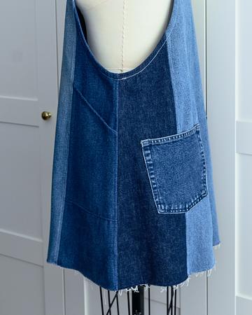 Sustainable patchwork denim shift dress with frayed hem and front pocket on a white mannequin.