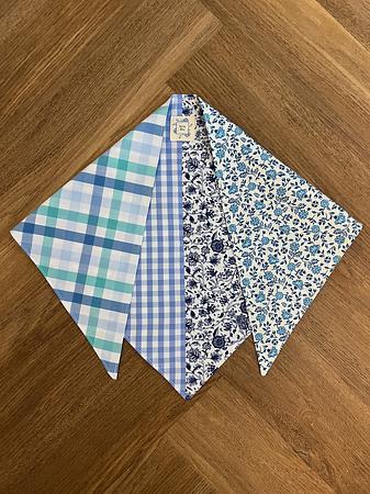 Blue and white patterned triangle scarf laid out on a wooden surface.
